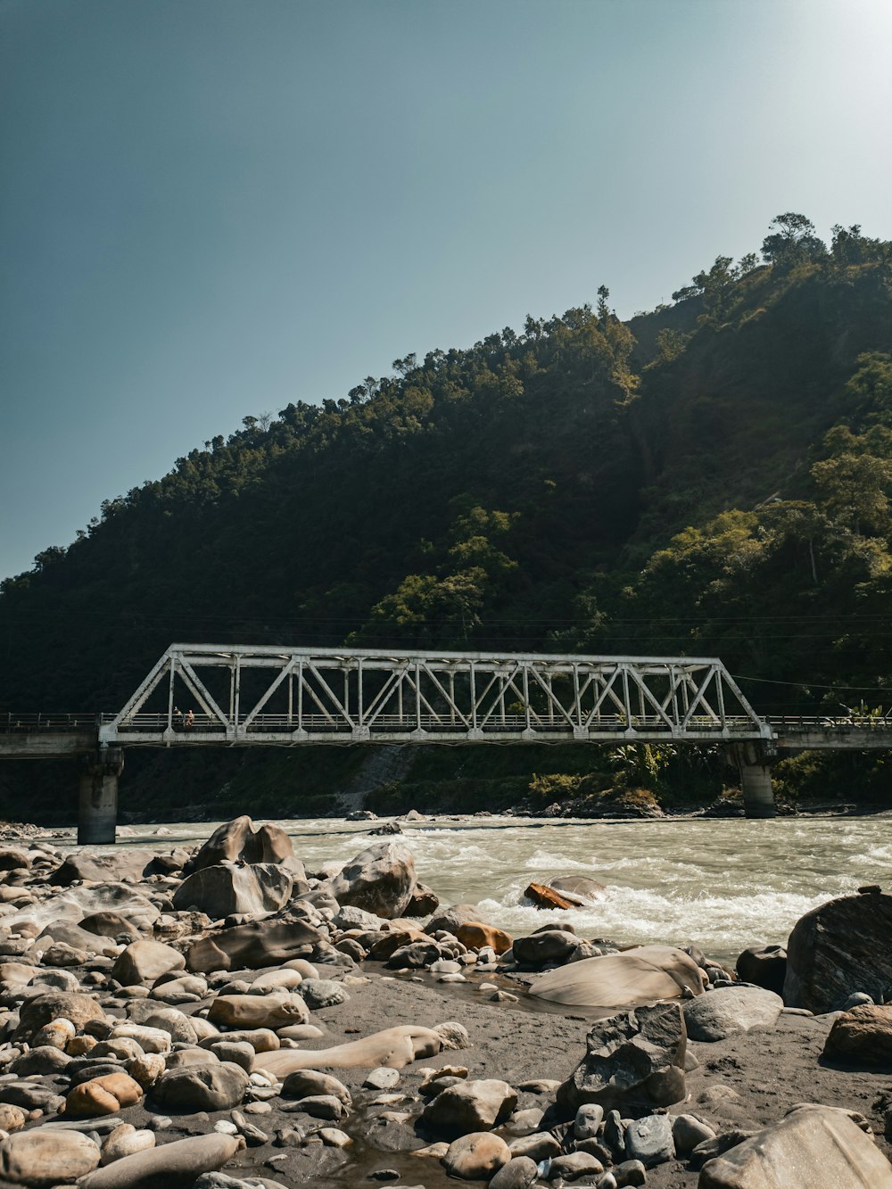 a bridge over a river with a mountain in the background