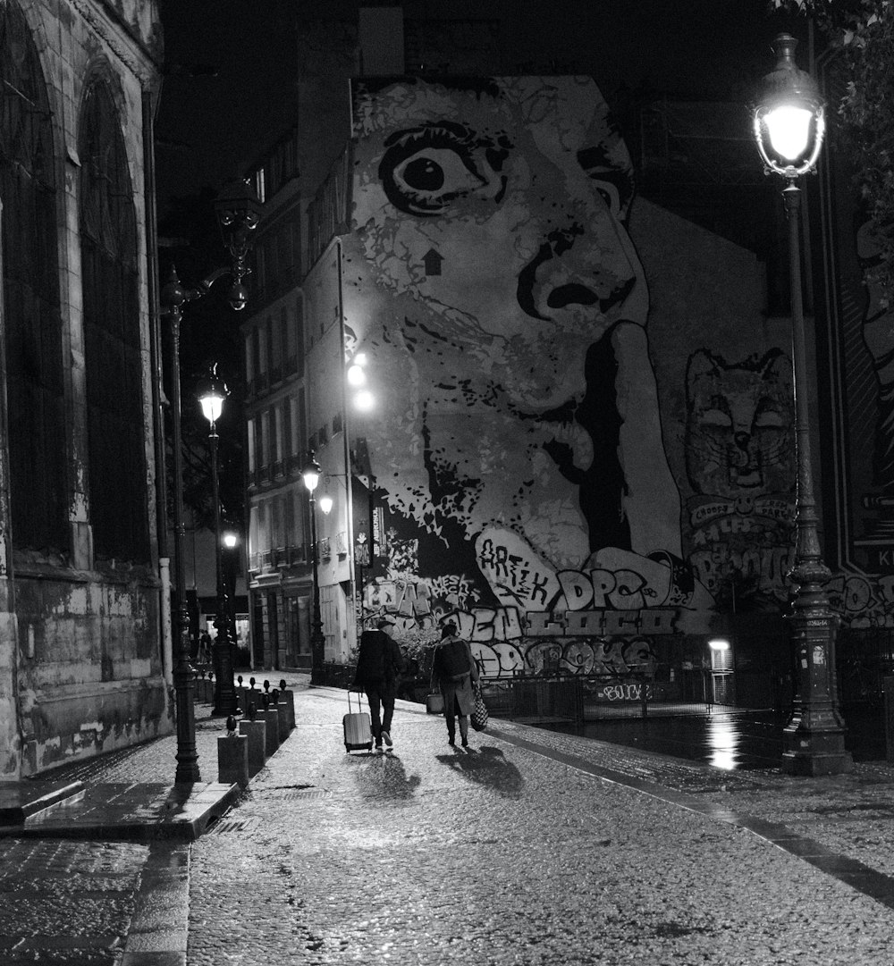 a couple of people walking down a street at night