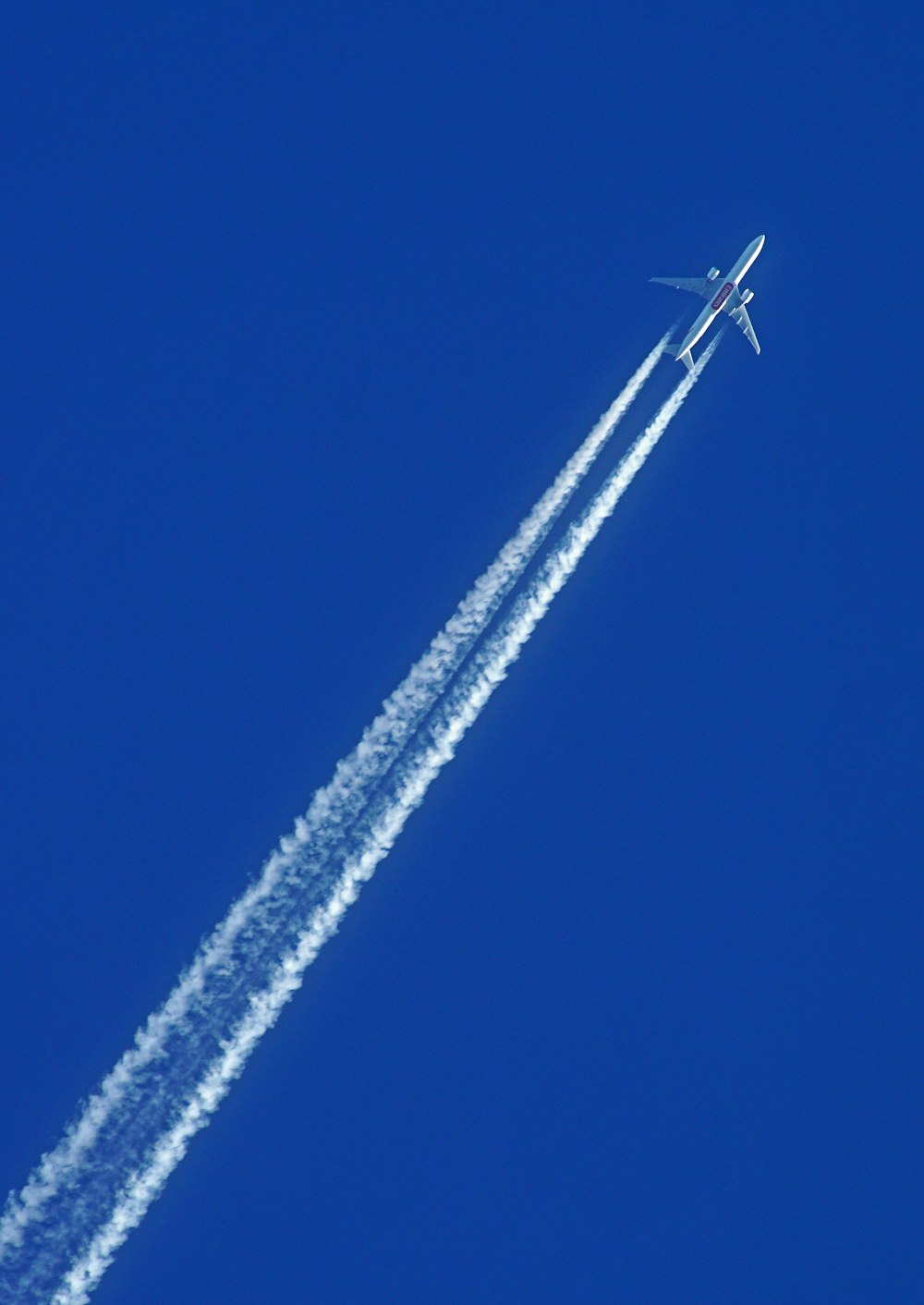 un jet che vola attraverso un cielo azzurro lasciando una scia di fumo
