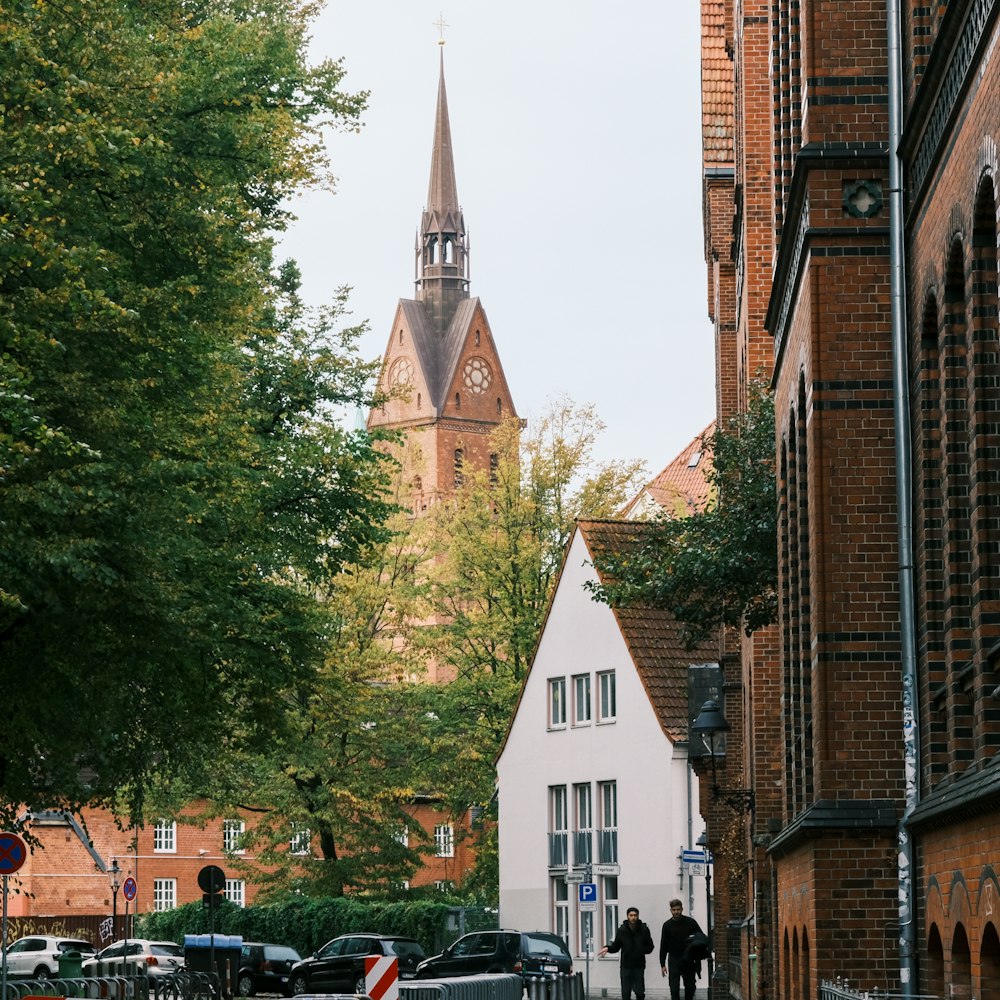 a couple of people walking down a street next to tall buildings