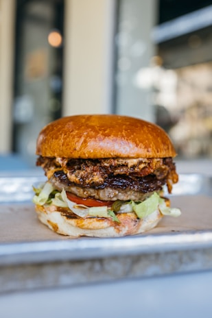 Juicy burger stacked with fresh ingredients, served on a rustic plate.