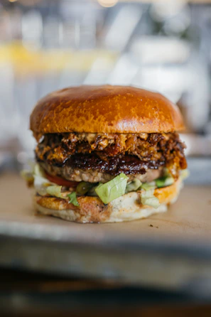 A juicy burger topped with caramelized onions and pickles, served on a rustic wooden board.