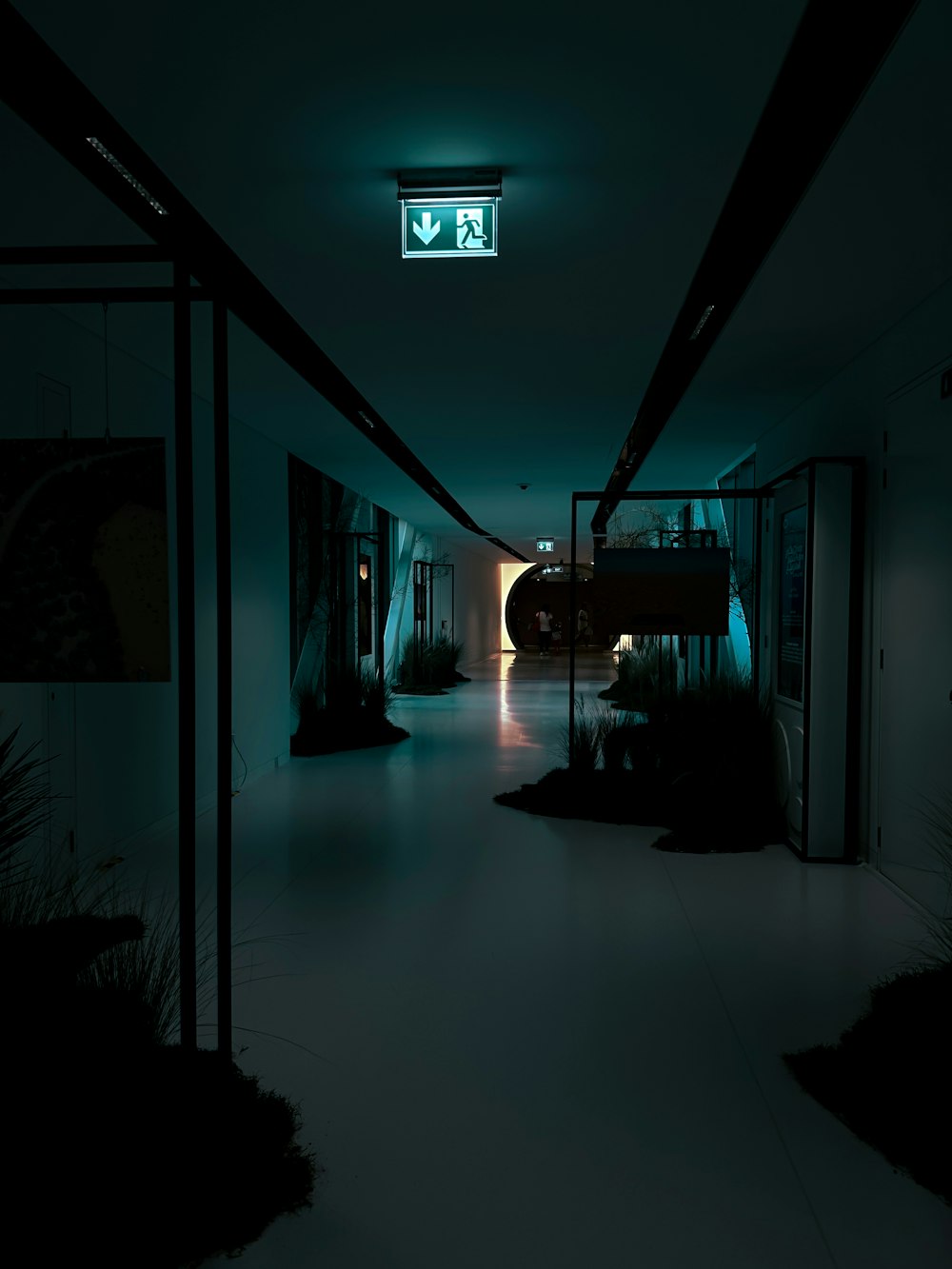 a dark hallway with a green light at the end