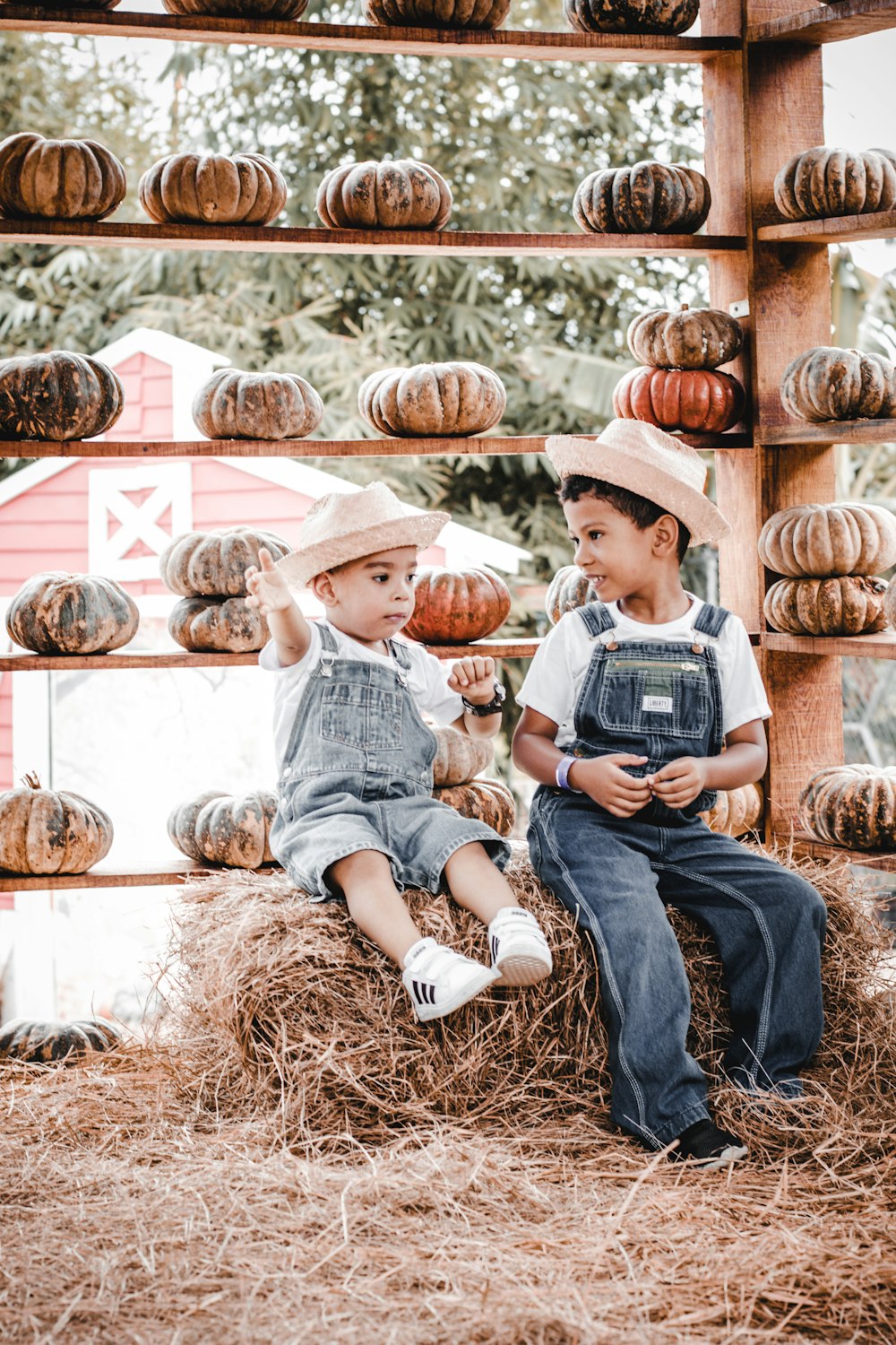 two young boys sitting on a pile of hay