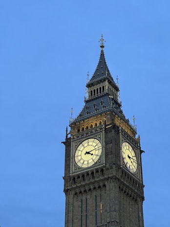 A close-up of a vintage clock tower against a bright blue sky.