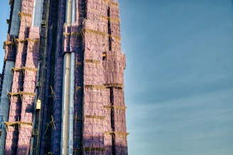 An elegant office building under construction with deep royal blue scaffolding accents.