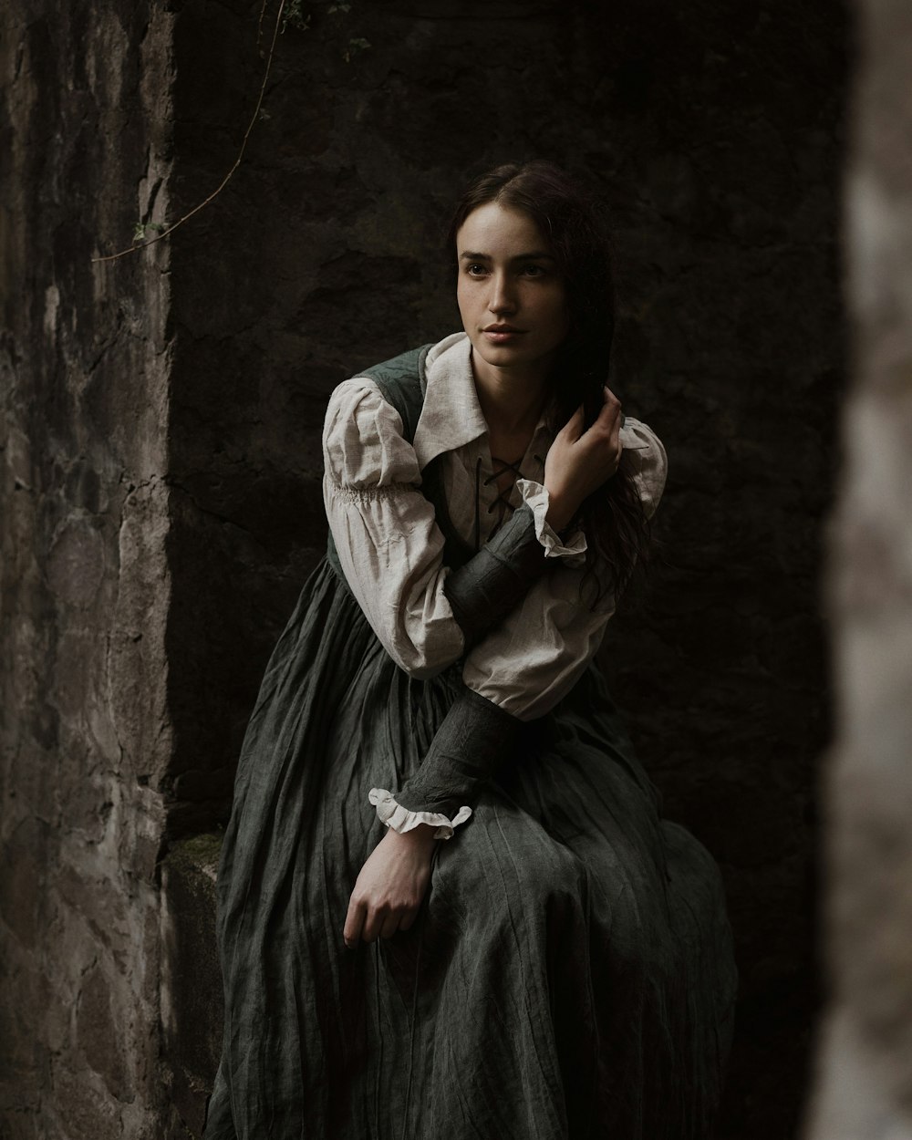 a woman in a dress sitting on a stone wall