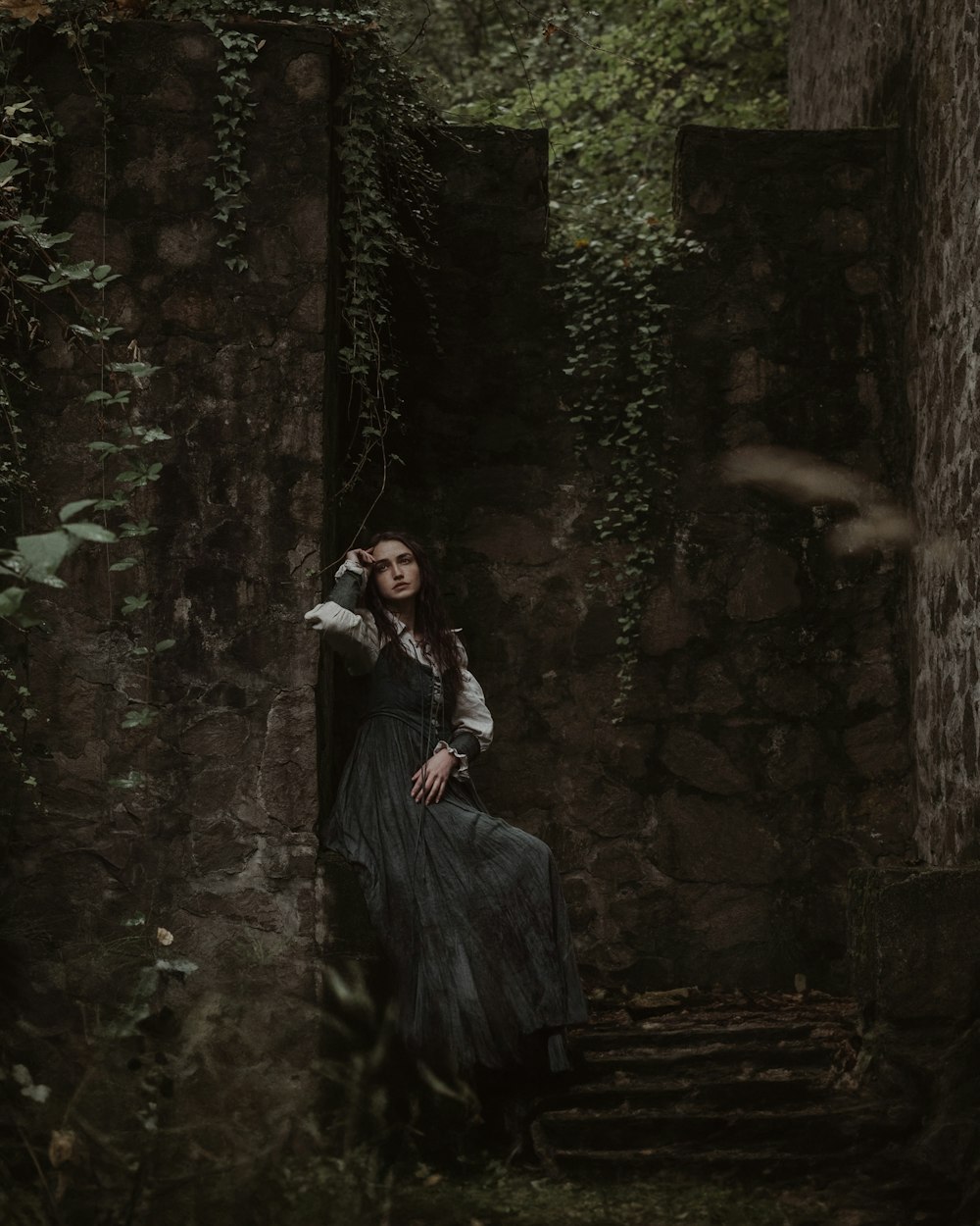 a woman in a black dress is sitting on a stone staircase