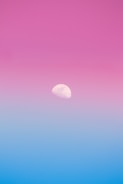 a pink and blue sky with the moon in the distance