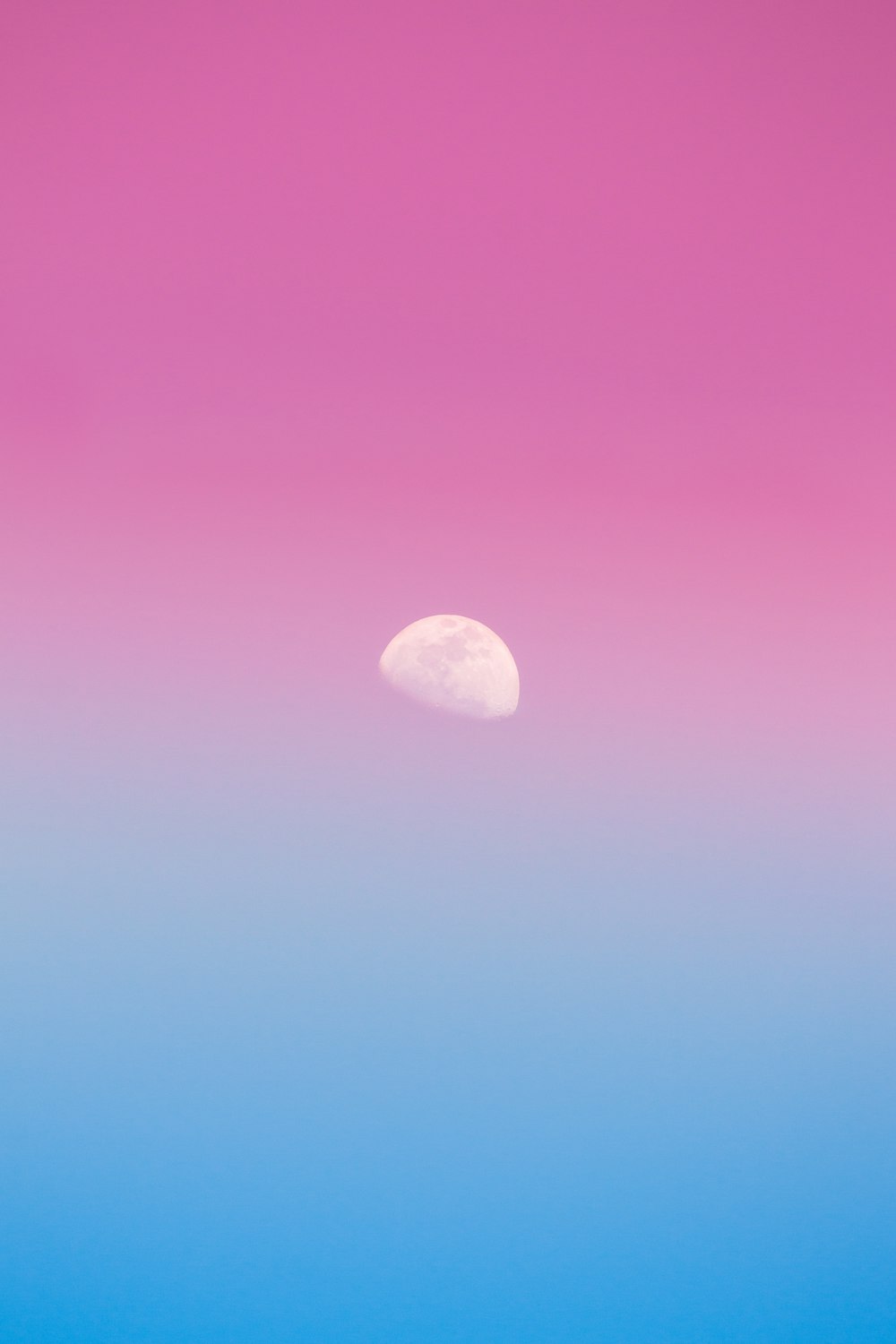 a pink and blue sky with the moon in the distance