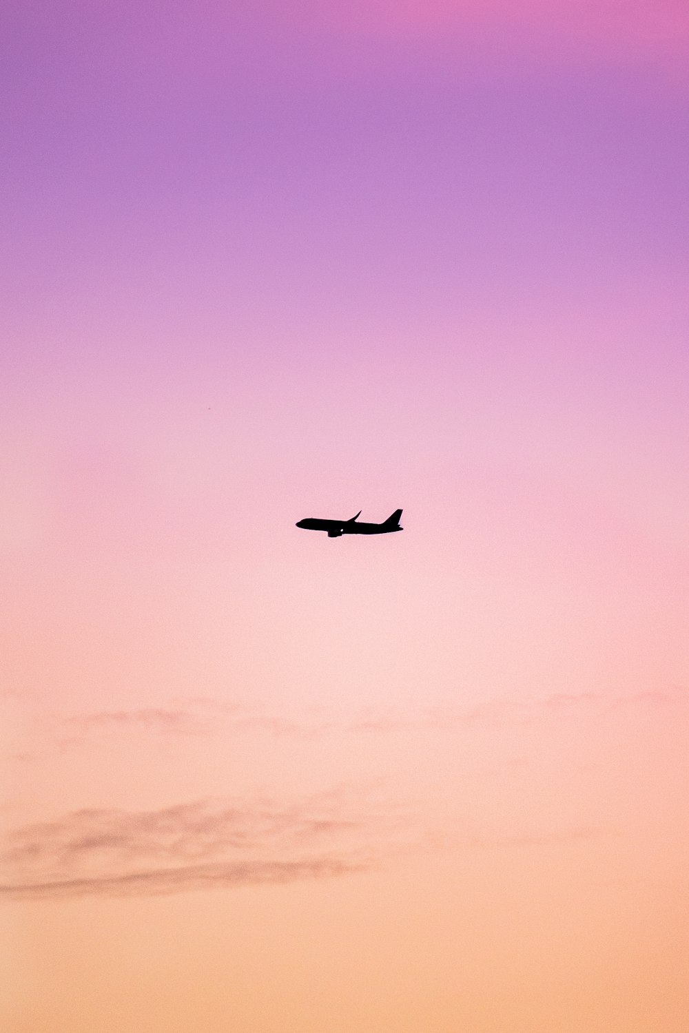 a plane flying in the sky at sunset