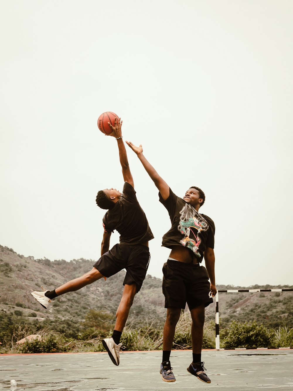 two young men playing basketball in a parking lot