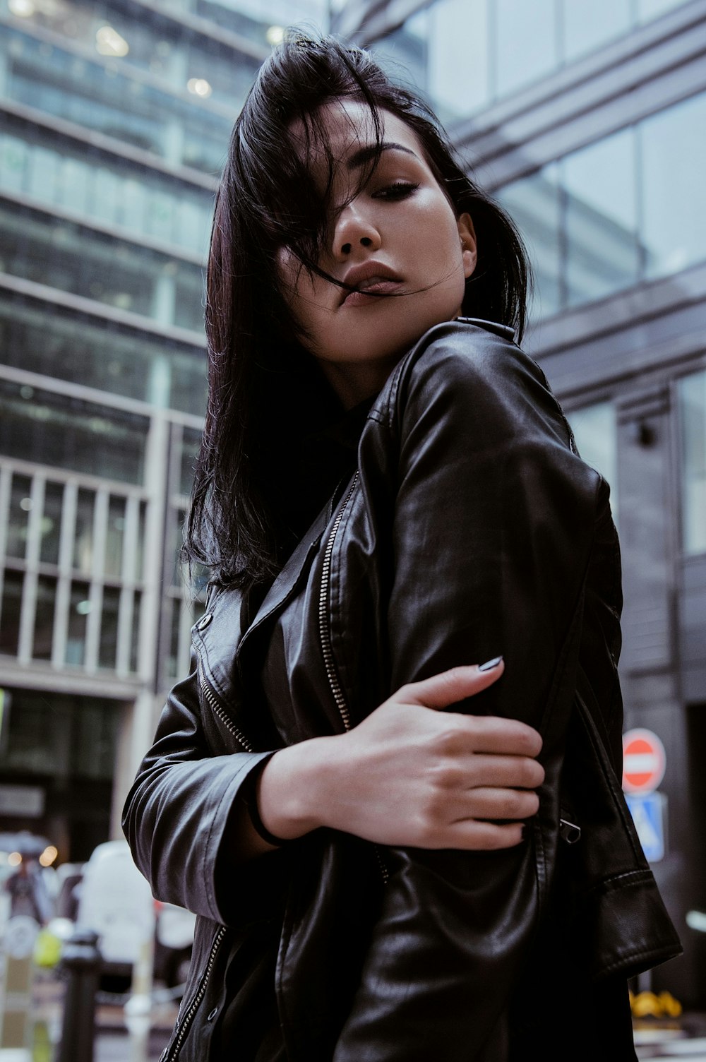 a woman wearing a black leather jacket and smoking a cigarette