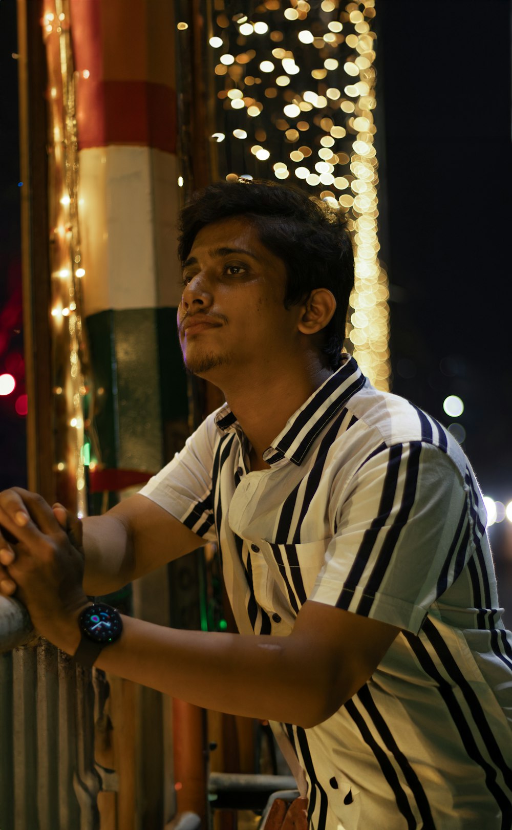 a man standing next to a fence with a cell phone in his hand