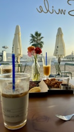 A cozy brunch table set outdoors with fresh pastries, smoothies, and sunlight filtering through trees.