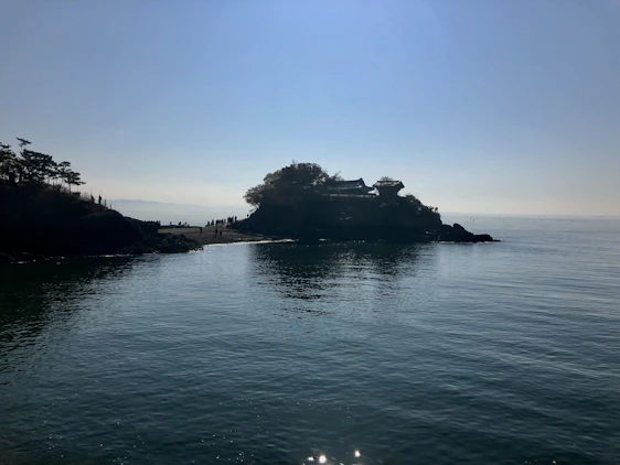 A serene coastal view of the Aeolian Islands with a small group engaged in a hiking workshop under sunny skies.