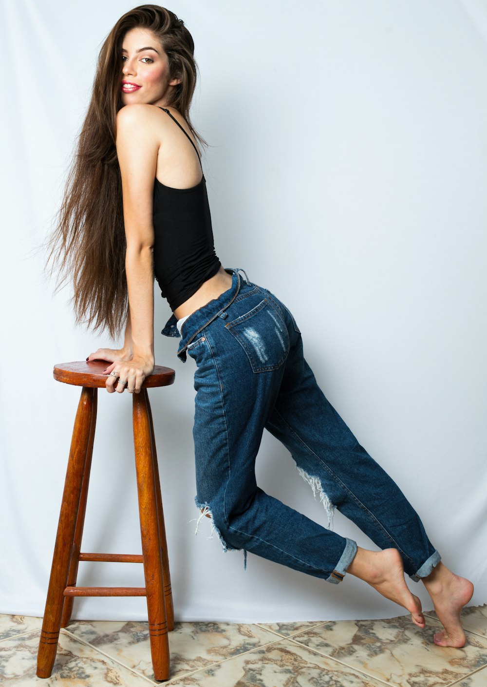 a woman leaning on a stool and posing for a picture