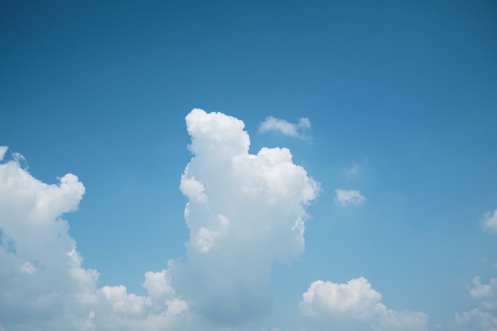 un aereo che vola nel cielo con una nuvola sullo sfondo