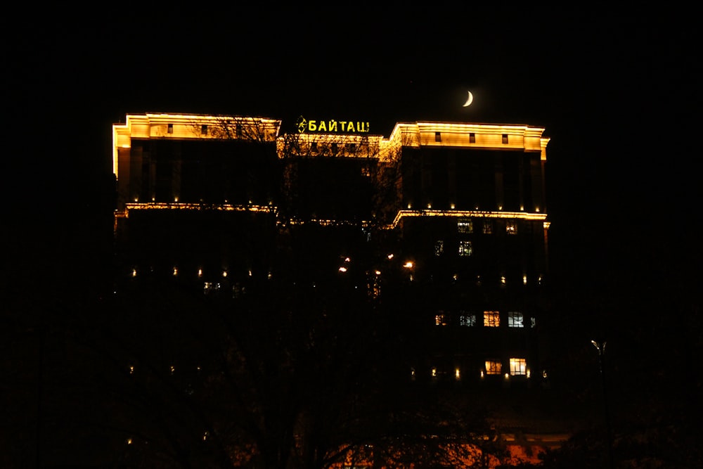 a building lit up at night with the moon in the sky