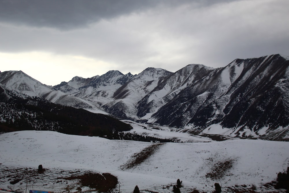 a snow covered mountain range under a cloudy sky