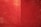 A complex network of thin red threads crisscrossing in various directions, creating a dense, web-like appearance on a red background. The lines vary in thickness and density, with some areas appearing more concentrated than others. The scene is divided into two halves by a subtle vertical line.