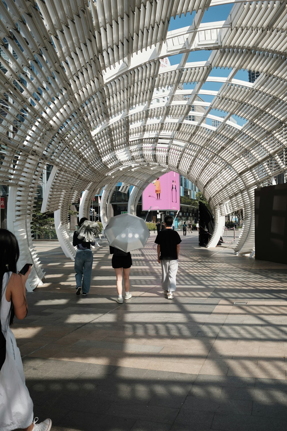 a group of people walking down a walkway holding umbrellas