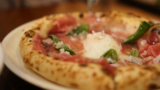 Overhead shot of a rustic pizza topped with vibrant ingredients on a dark, elegant background.