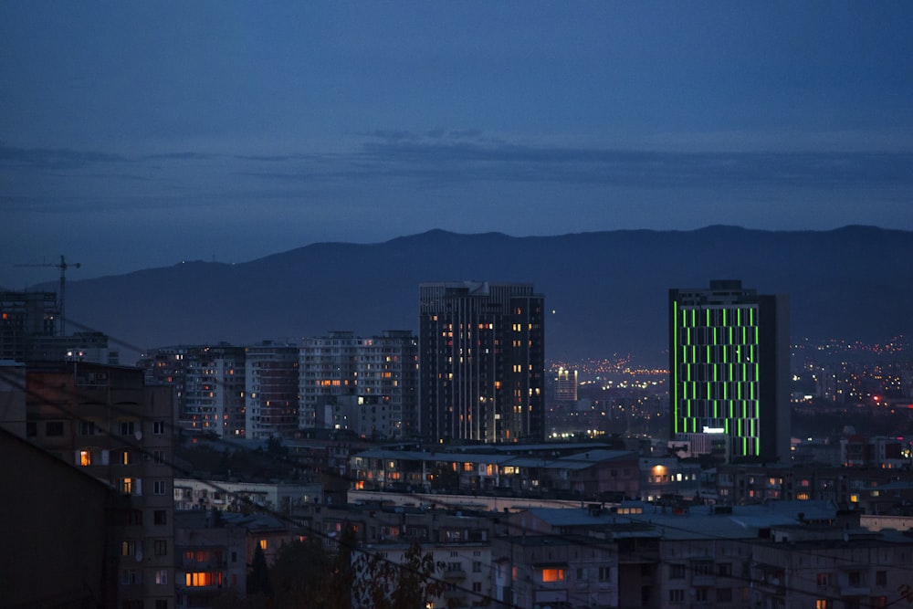 uma vista de uma cidade à noite com montanhas ao fundo