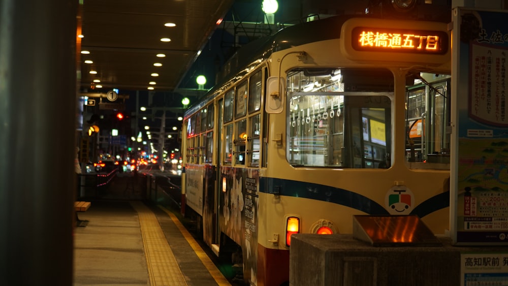 a yellow and blue bus parked at a bus stop