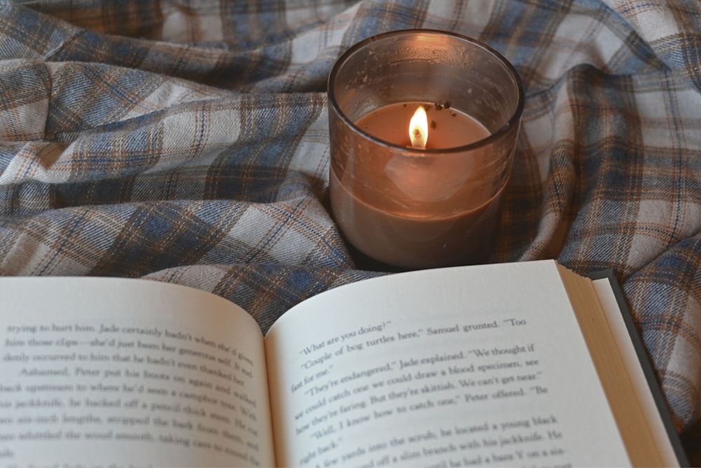 an open book and a lit candle on a blanket