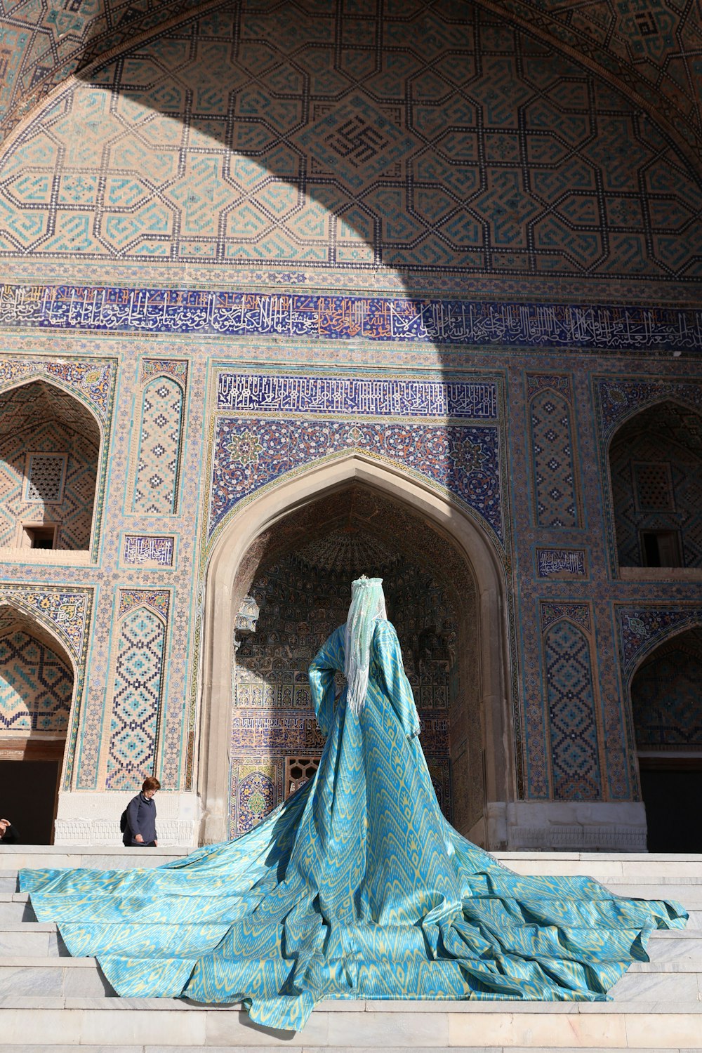 uma mulher com um vestido azul em frente a um prédio
