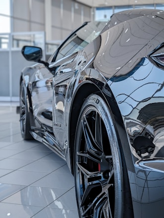 Close-up of shiny alloy wheels and branded tyres displayed against a sleek car backdrop in a Chennai showroom.