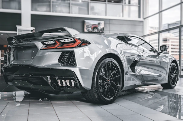Shiny silver sports car gleaming under showroom lights with a gold-accented interior.