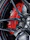 Close-up of a mechanic replacing brake pads on a car wheel outdoors with blue and red metallic accents.