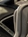 A close-up view of a gray leather car interior, focusing on the stitching detail and texture of the material. The background is slightly blurred, showing parts of the dashboard and console.