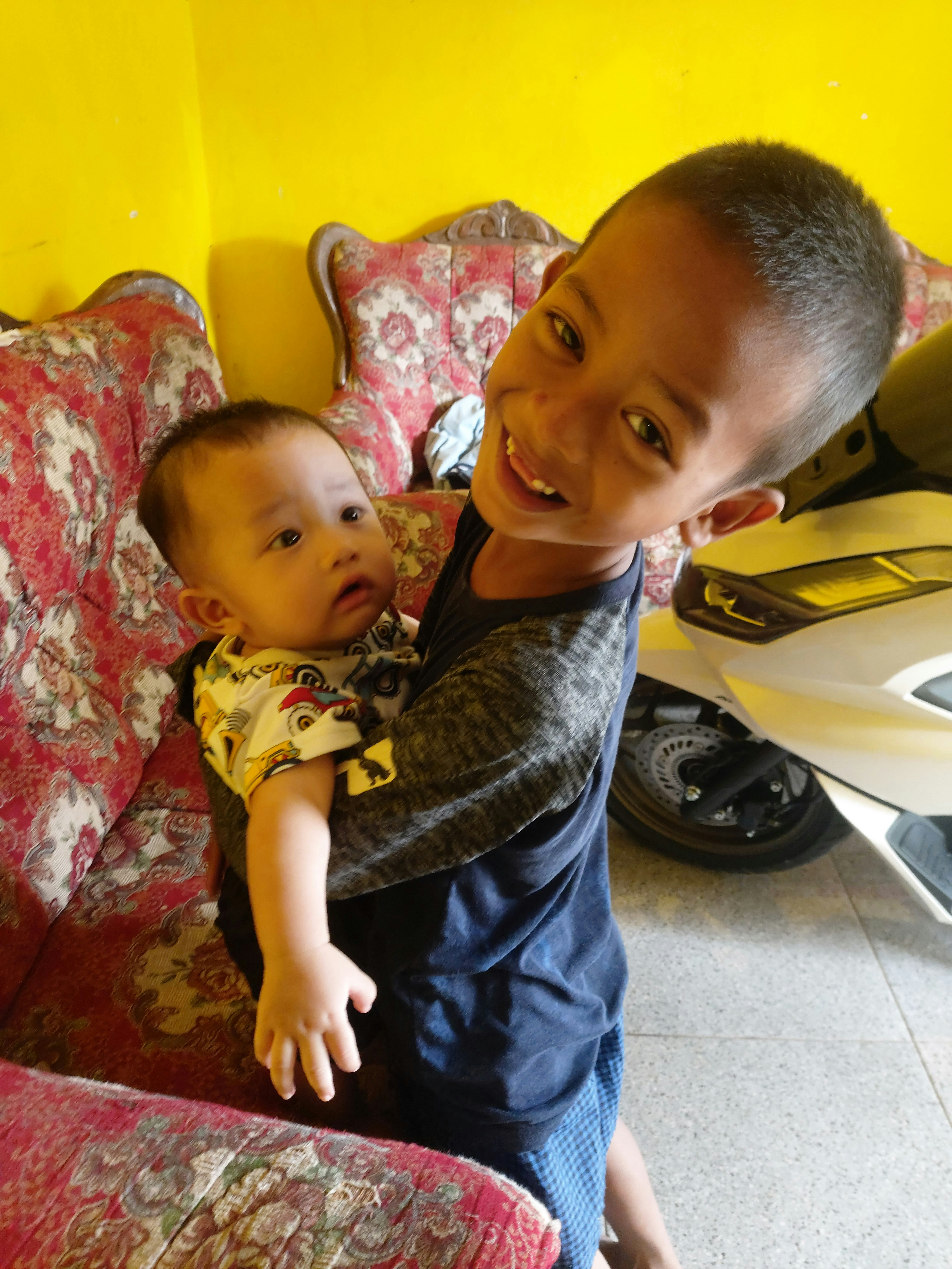A smiling caregiver gently holding hands with a young boy in a bright, cozy living room.