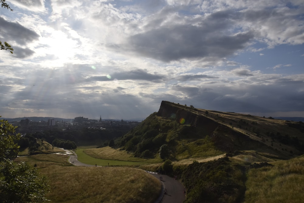 the sun shines through the clouds over a hill