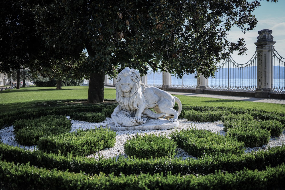 une statue d’un lion au milieu d’un jardin