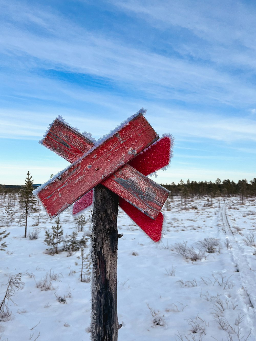 a wooden pole in the middle of a snowy field