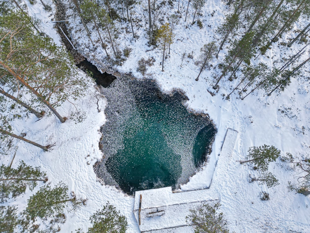an aerial view of a snow covered lake surrounded by trees