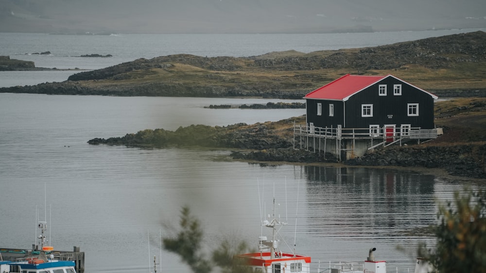 a red house sitting on top of a hill next to a body of water