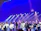 A diverse group of teenagers rehearsing a musical number with bright stage lights.
