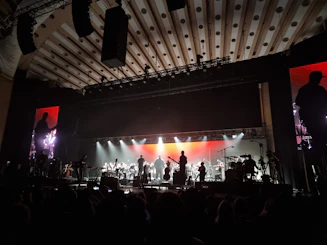 A lively orchestra performing on stage with colorful lighting.