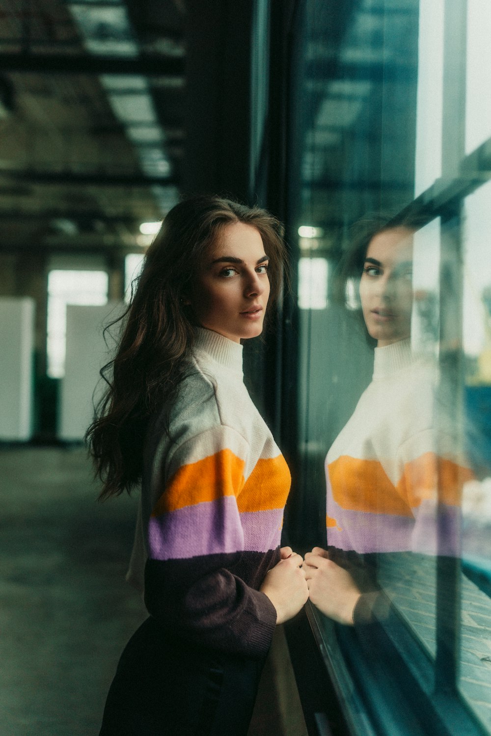 a woman standing next to a window in a building