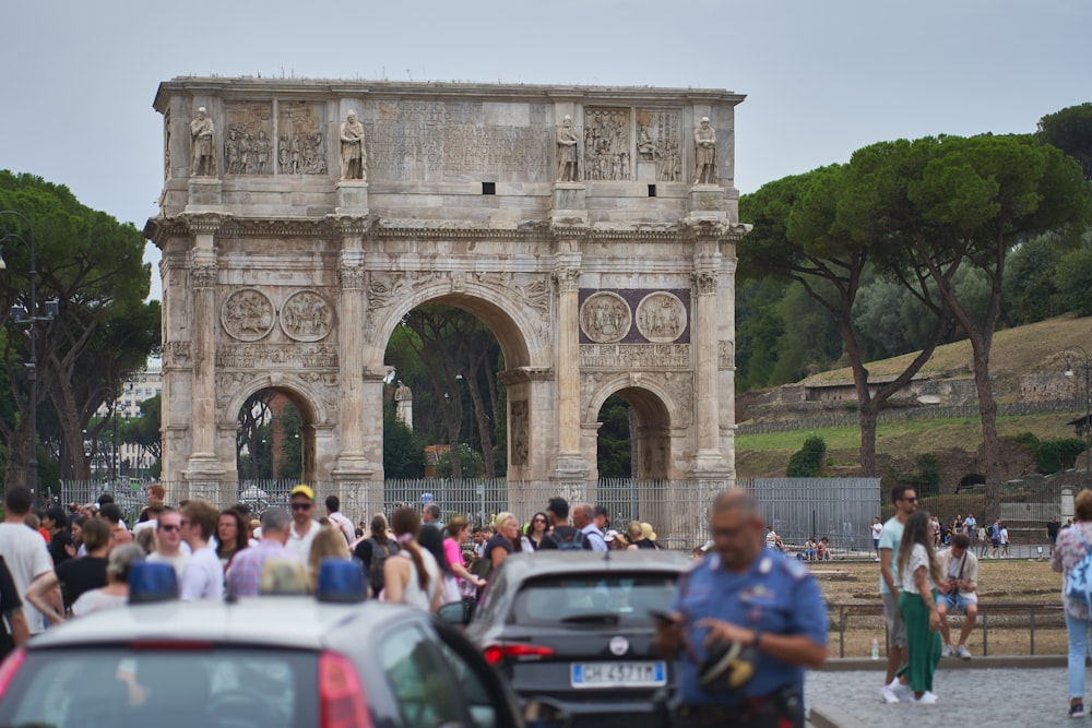 a crowd of people walking around a stone arch