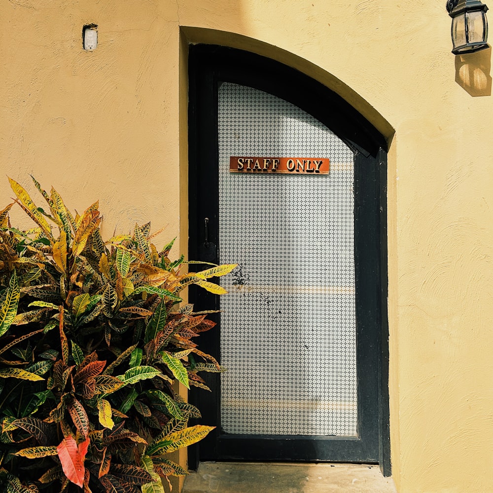 una puerta con un letrero junto a una planta en maceta