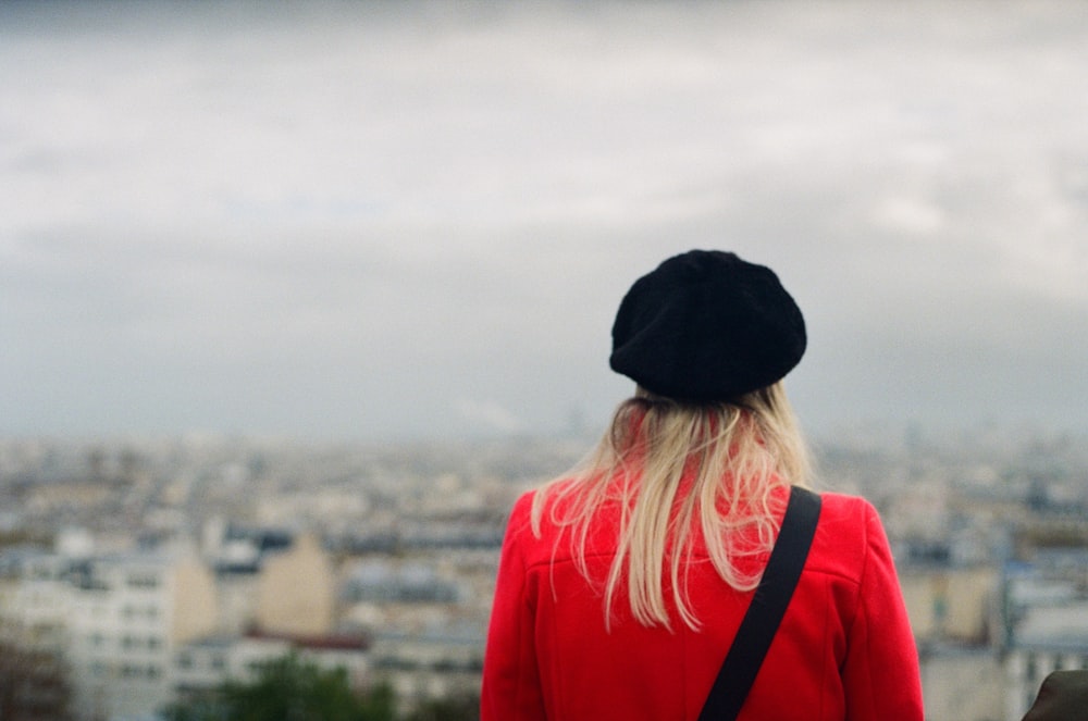 a woman in a black hat looking at the city