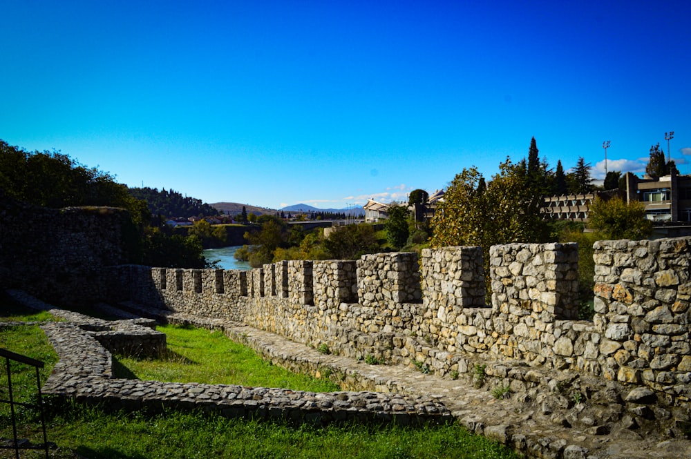 a stone wall next to a body of water