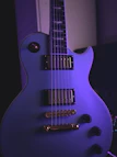 Close-up of silver and violet guitar picks glowing under dark lighting