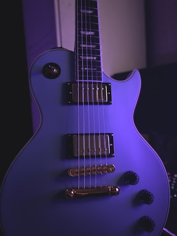 Close-up of a colorful electric guitar with green and purple accents on stage.